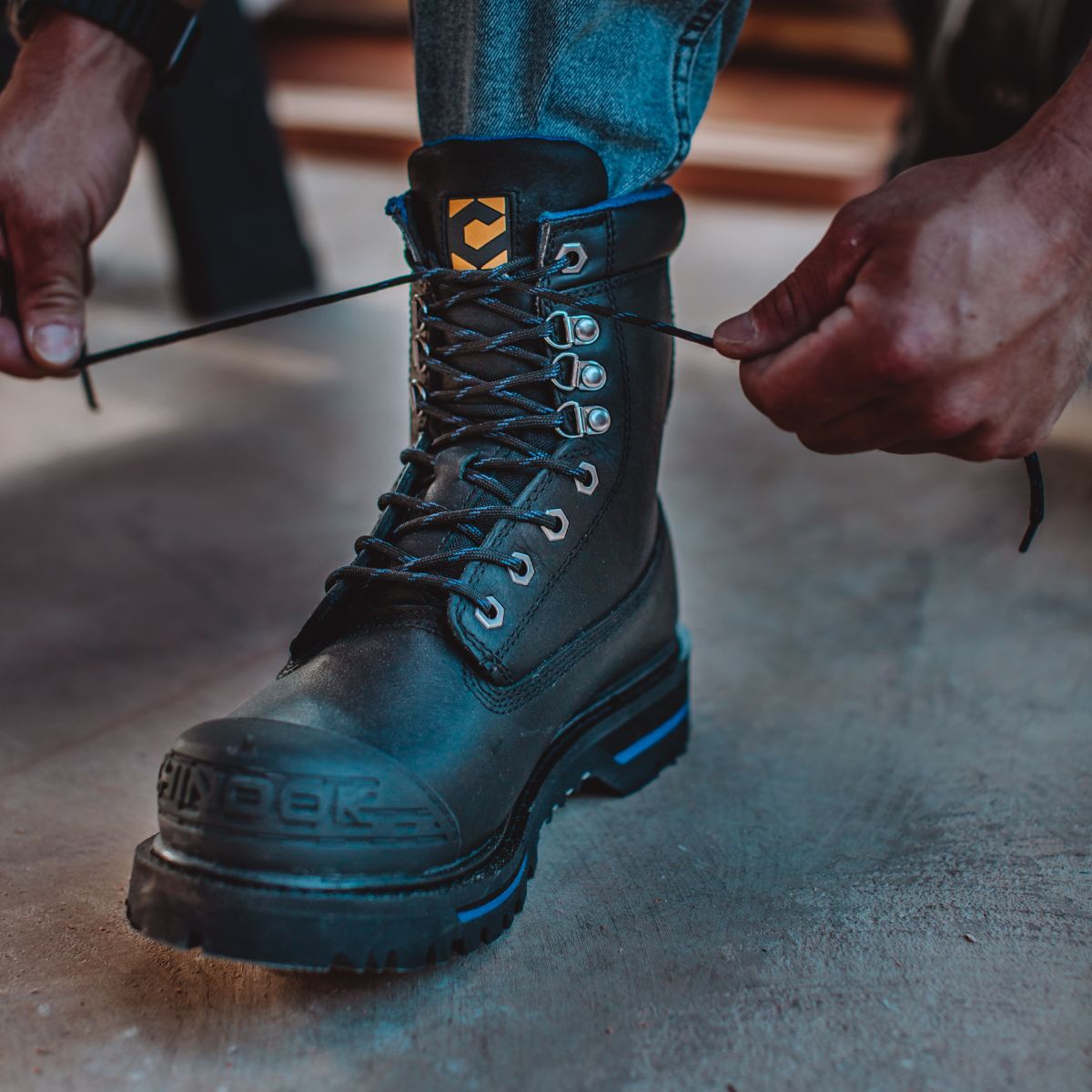 A man lacing up the Tarantula 8" Steel Toe Men’s Waterproof Work Boot in Black. The boot features a sturdy steel toe, durable leather, and a rugged design, built for tough work environments and all-day protection.